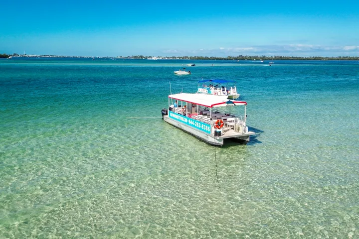 Floating barge with people in clear shallow water near shore on a sunny day.