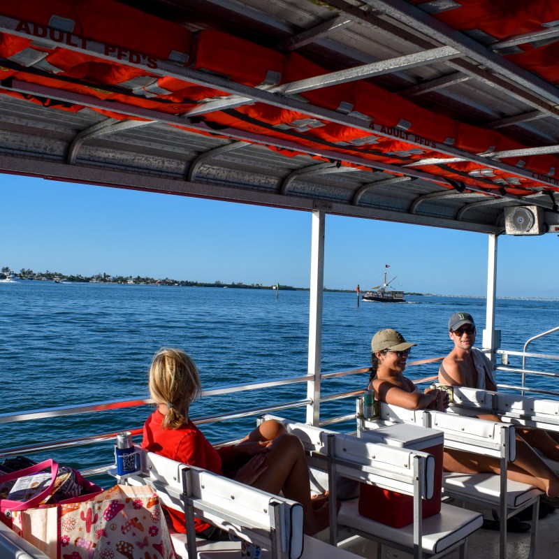 People sitting on a boat enjoying a sunny day with water and distant land visible.